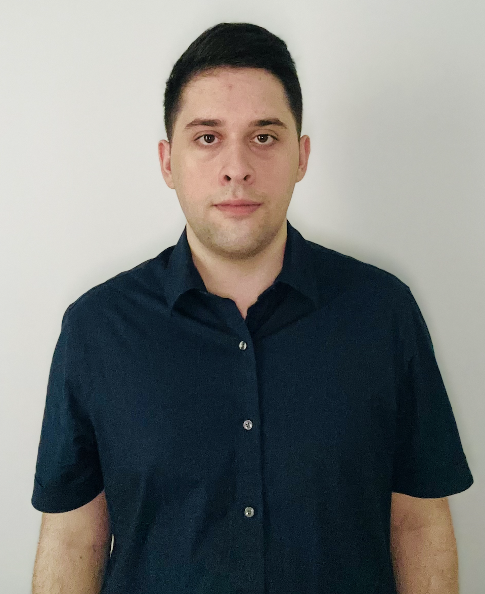 Person in a dark blue shirt standing against a plain white background.