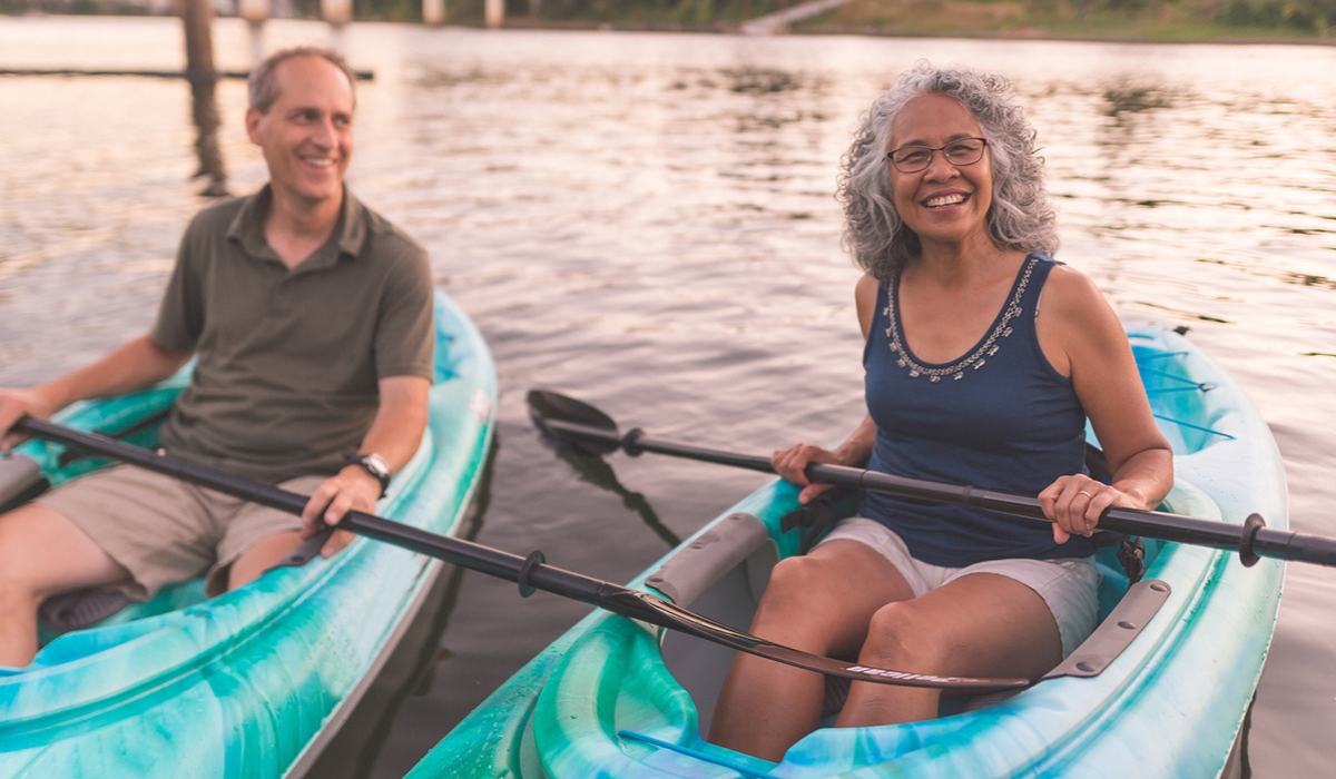 An older man and woman sitting in kayaks and smiling