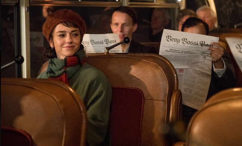 Woman on bus looking at people holding newspapers.