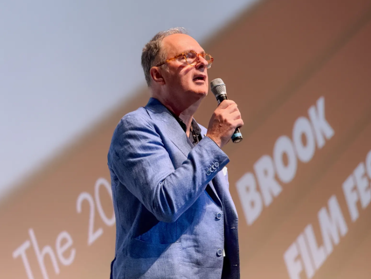 Man in blue jacket on stage holding mic